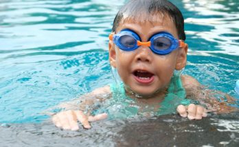 Kind fröhlich mit Schwimmbrille - Schwimmen lernen - Spielundlern.de