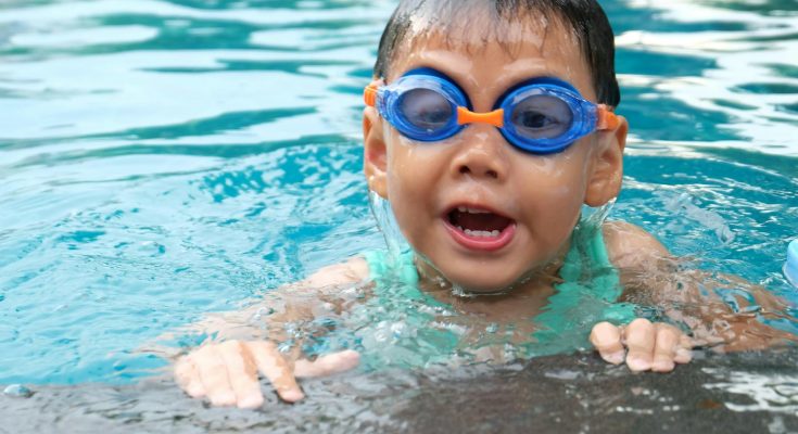 Kind fröhlich mit Schwimmbrille - Schwimmen lernen - Spielundlern.de