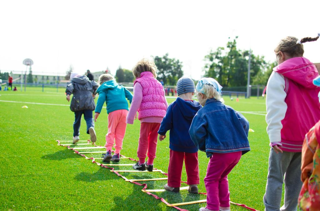 Kinder laufen eine Koordinationsleiter entlang.