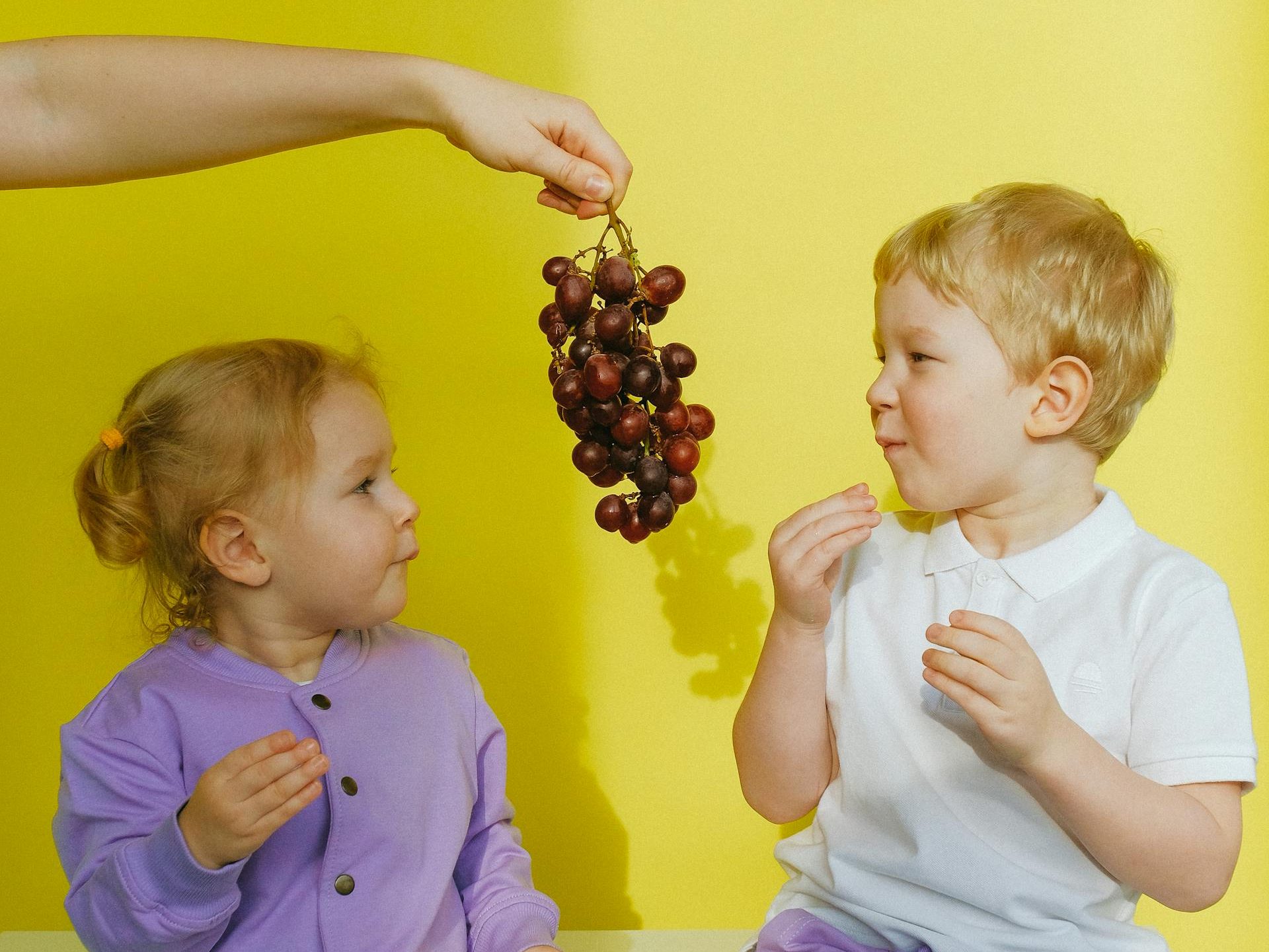 Zwei Kinder essen von einer Traube.