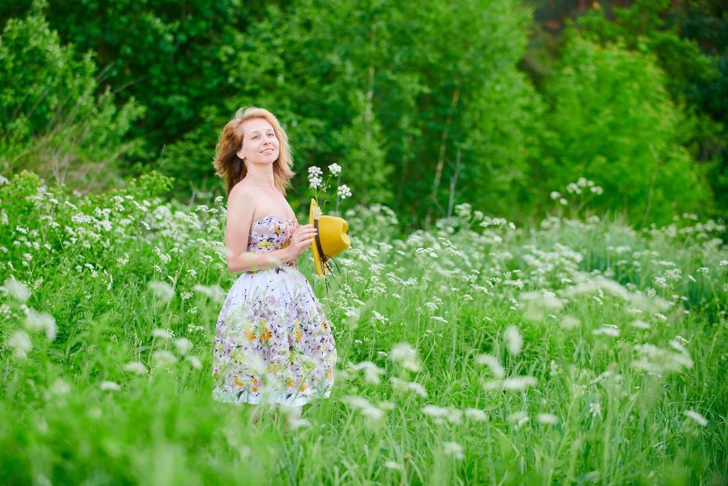 Eine Frau steht in einem Wildblumenfeld und schaut glücklich.