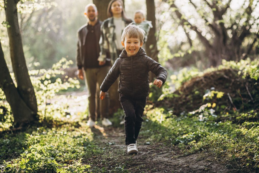 Ein Kind mit seiner Familie im Wald rennt auf die Kamera zu.