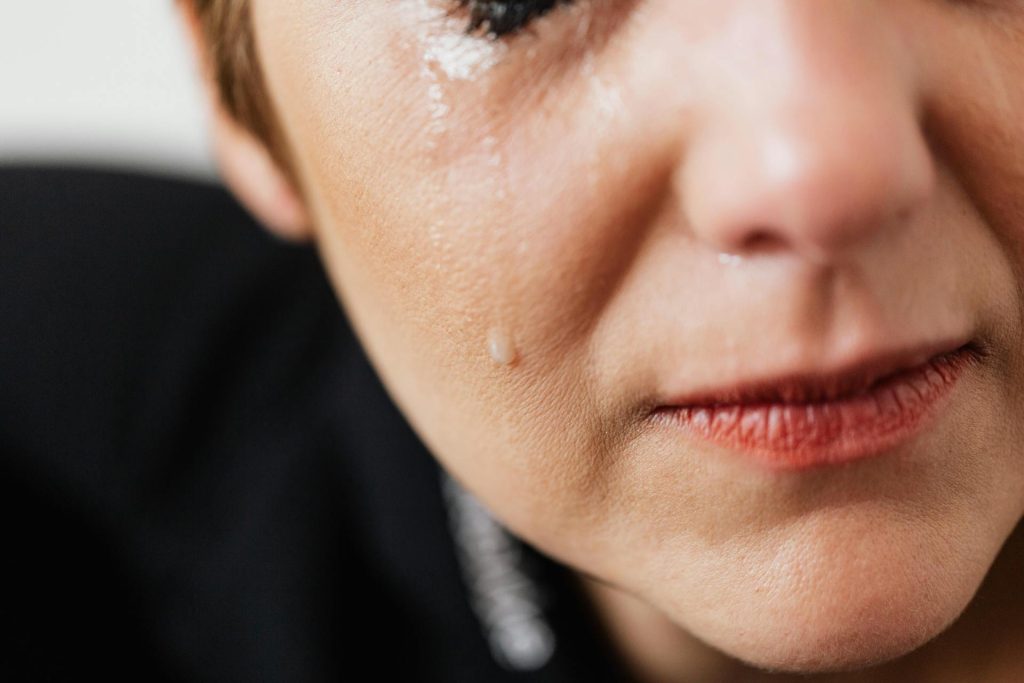 Auf der Wange einer Frau perlt eine Träne herunter.