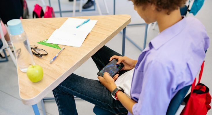 Schüler nutzt Handy in der Schulstunde.