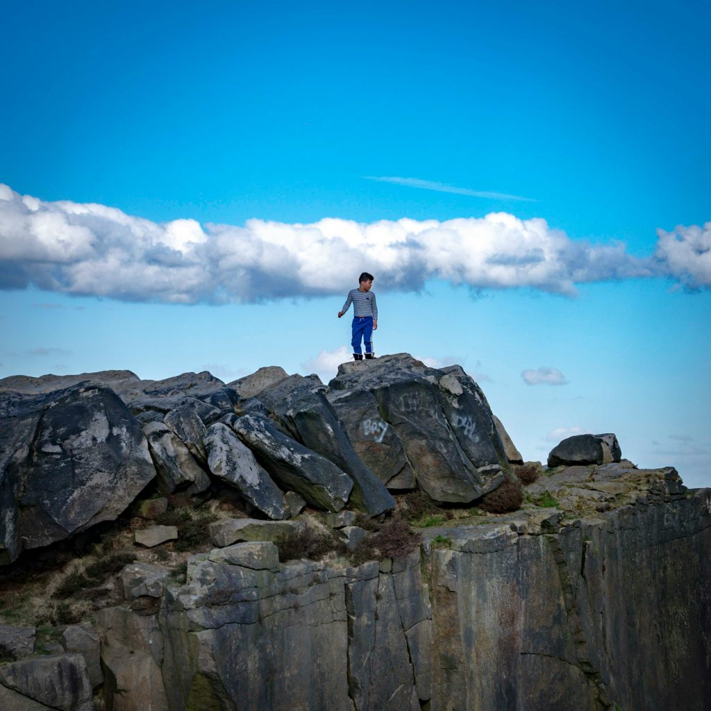 Ein Mann auf einem Felsen, über ihn eine Wolke.